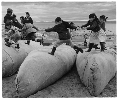 Kids playing on packed Hudson's Bay Company canoes